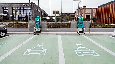Zwei Ladesäulen von Compleo stehen an einem Parkplatz bereit.